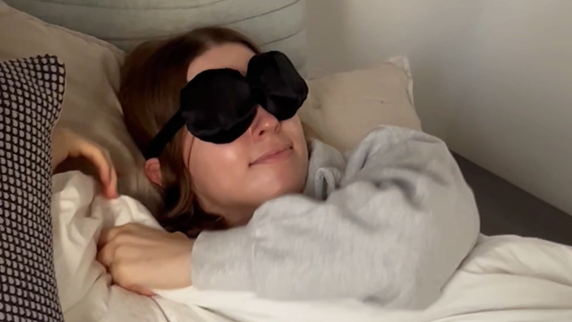 Person wearing a silk sleep mask goggle while resting in bed